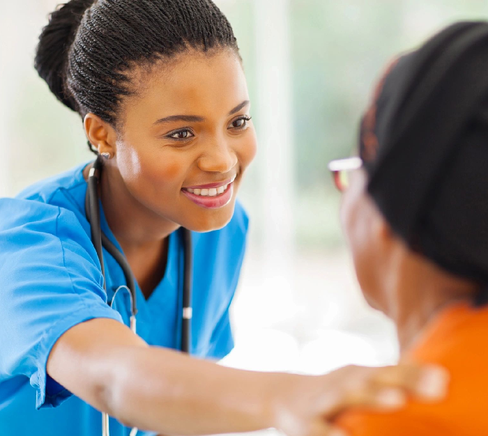 A woman in scrubs is smiling at someone.